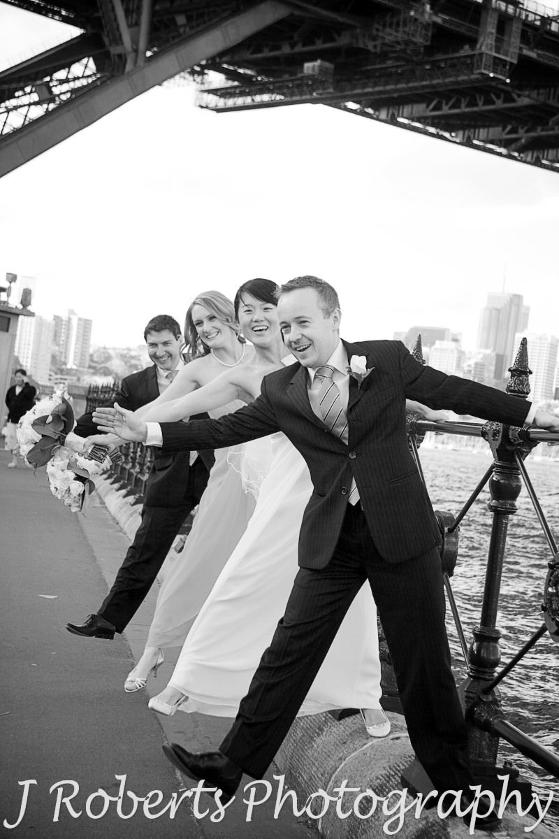 Bridal party swinging off the fence at Dawes Point - wedding photography sydney